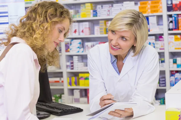Pharmacist showing prescription to a customer