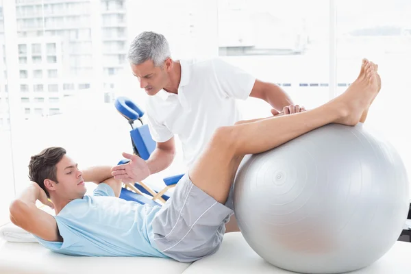 Therapist helping his patient with exercise ball