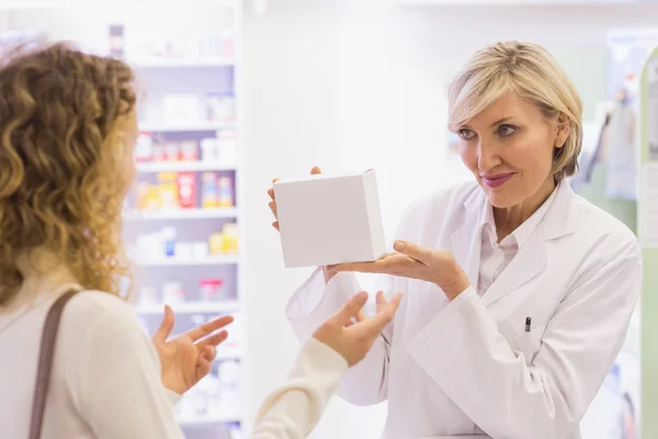 Pharmacist with bottle of drugs talking to customer