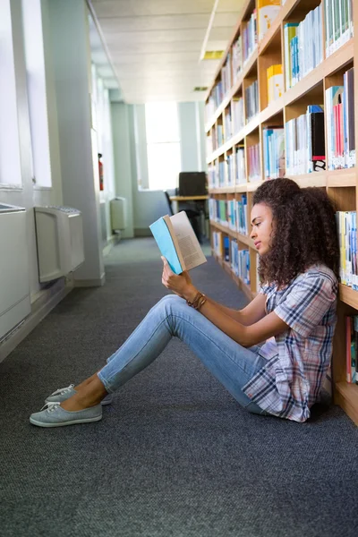 Student sitting on floor in library and reading