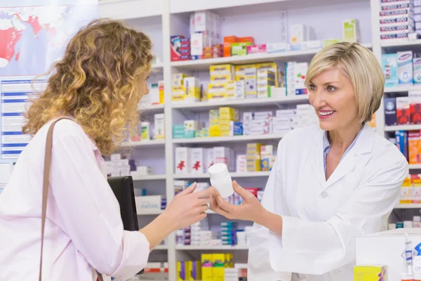 Smiling pharmacist holding a medicine jar