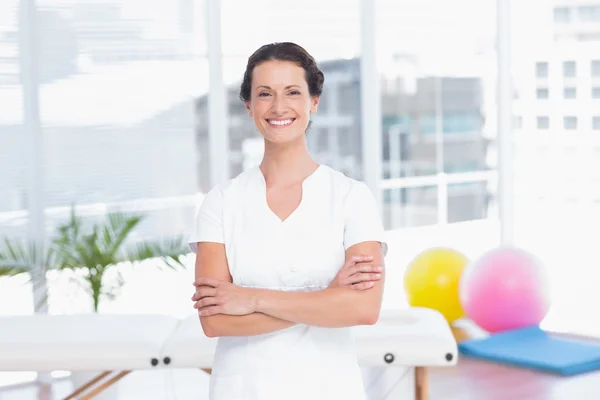 Smiling doctor standing arms crossed and looking at camera