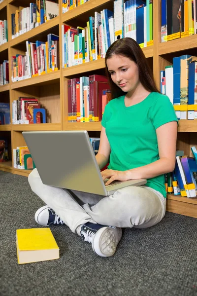 Student sitting on floor in library using laptop