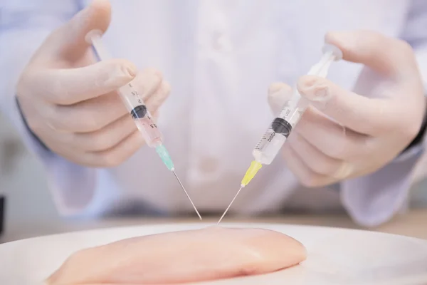 Scientist injecting piece of meat