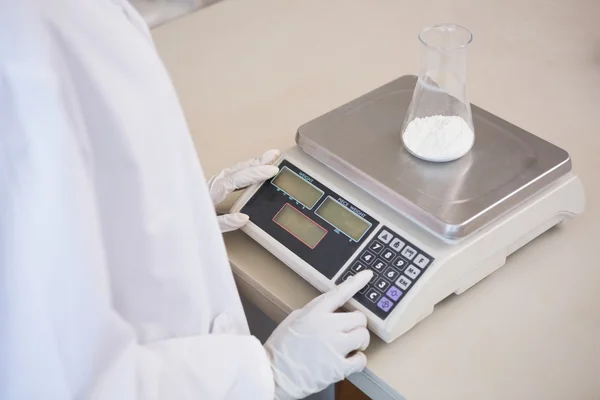 Scientist weighing beaker with white powder