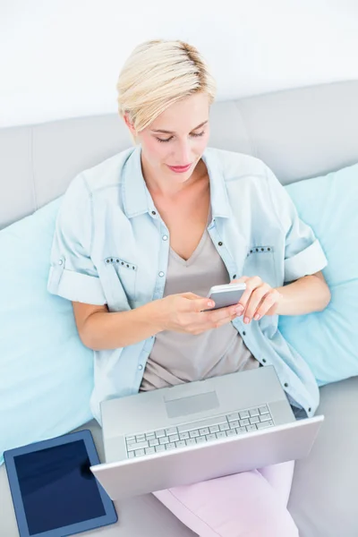 Woman using laptop and mobile phone