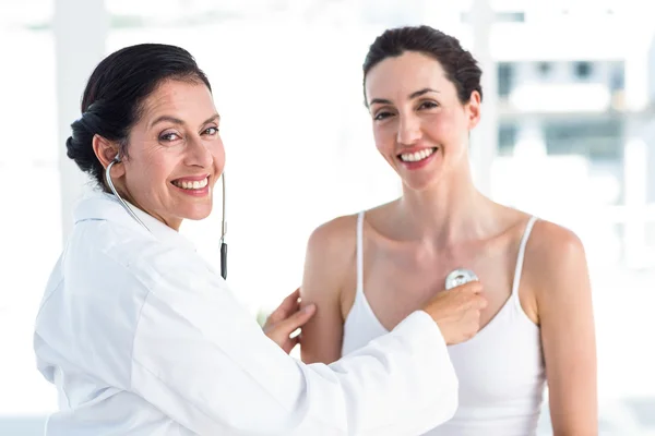 Doctor listening to patients chest with stethoscope