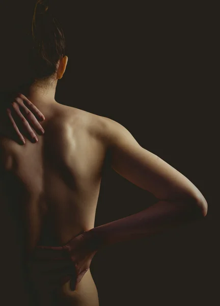 Nude woman with a back injury