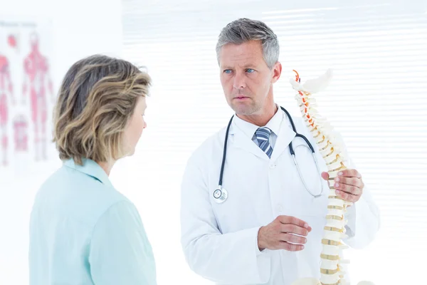 Doctor having conversation with his patient and showing spine mo