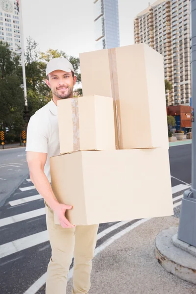 Composite image of delivery man carrying cardboard boxes