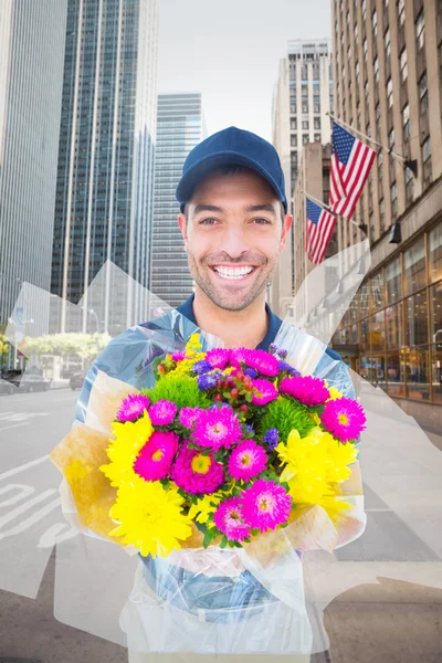 Composite image of happy delivery man holding bouquet