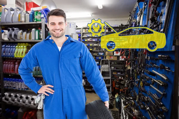 Smiling male mechanic holding tire