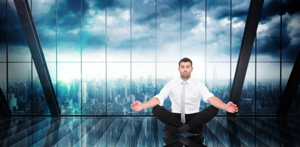 Composite image of businessman meditating in lotus pose