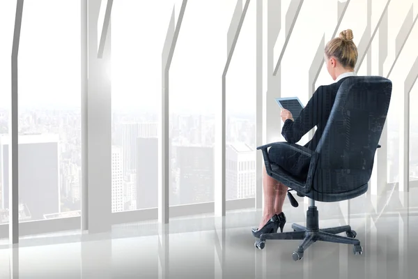 Businesswoman sitting on swivel chair with tablet