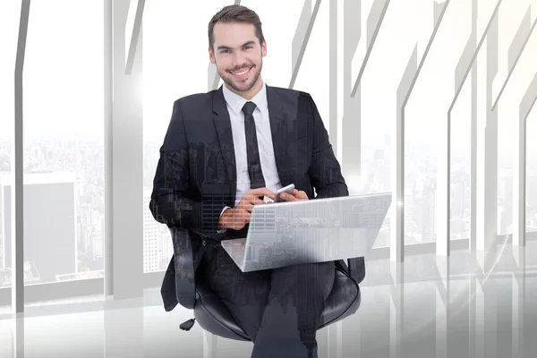 Happy businessman with laptop using smartphone