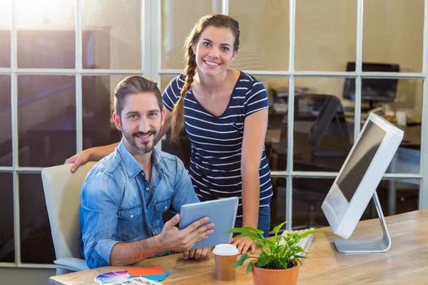 Smiling colleagues working together on tablet