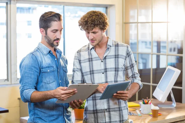 Business team looking at clipboard and tablet