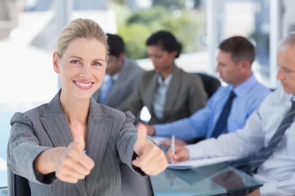 Businesswoman smiling at camera with colleagues behind