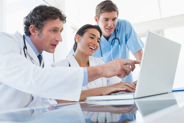 Team of happy doctors working on laptop computer