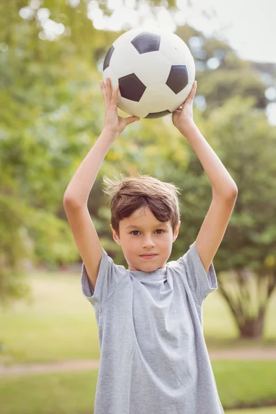 Boy looking at camera and holding a soccer ball in the park