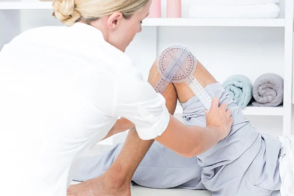 Doctor examining man leg with tool