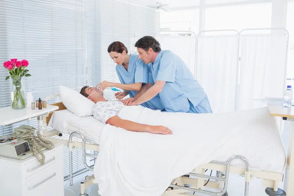 Worried doctors doing heart massage and holding oxygen mask