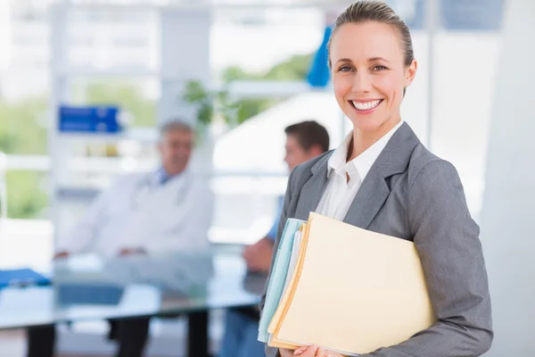 Smiling businesswoman holding files and looking at camera