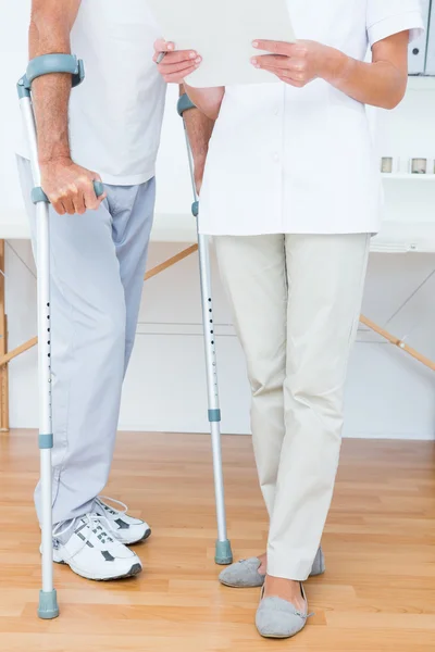 Doctor showing clipboard to her patient with crutch
