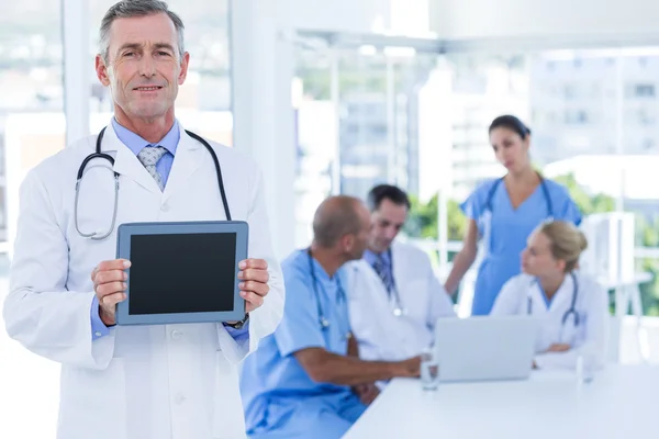 Doctor holding tablet computer while his colleagues works
