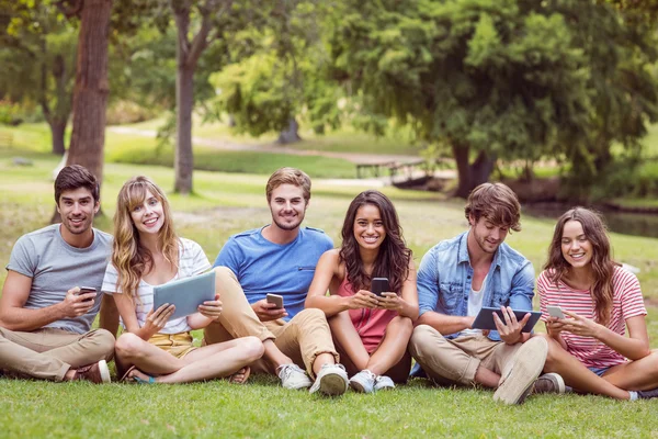 Happy friends in the park looking at tablet