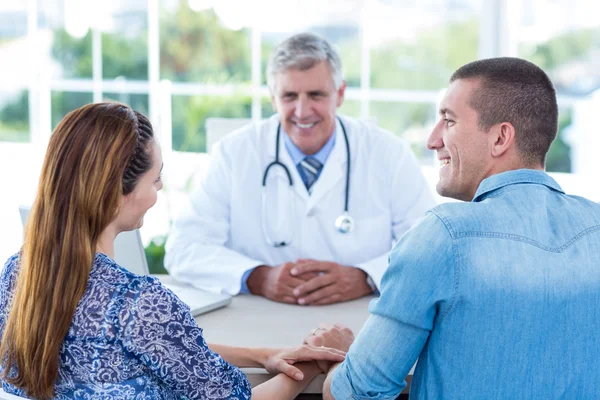 Smiling doctor looking at happy couple