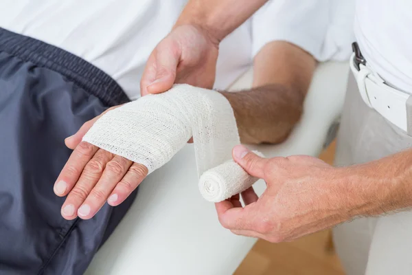 Doctor bandaging his patient hand