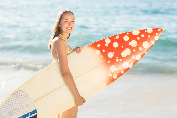Pretty brunette holding surf board