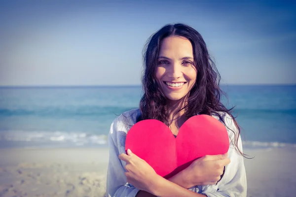 Woman holding heart card at beach