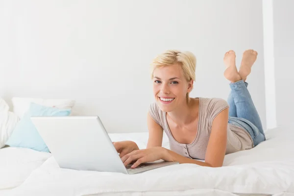 Smiling blonde woman using laptop