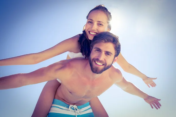 Handsome man giving piggy back to his girlfriend