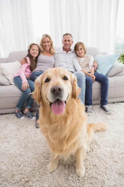 Family sitting on couch with retriever