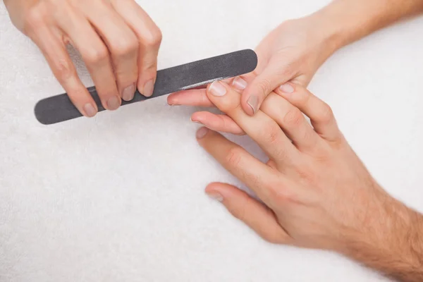 Manicurist filing customers nails