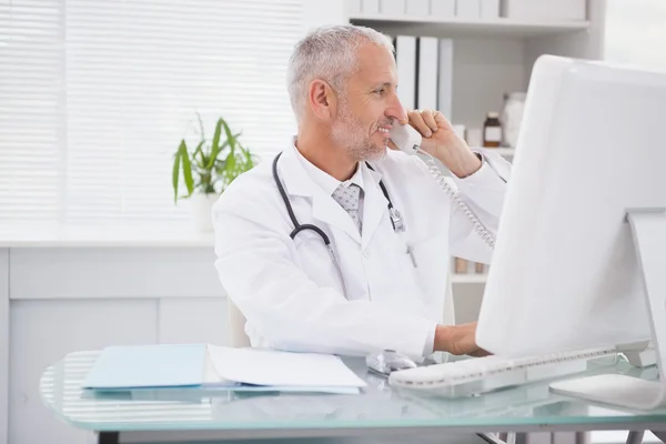 Doctor phoning and using computer
