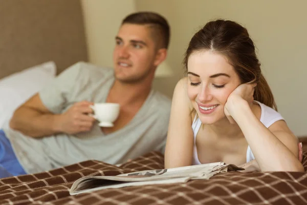 Couple reading newspaper in bed
