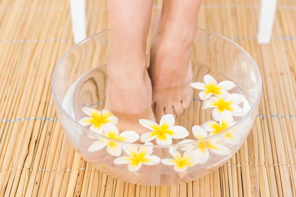 Woman washing her feet in a bowl of flowers