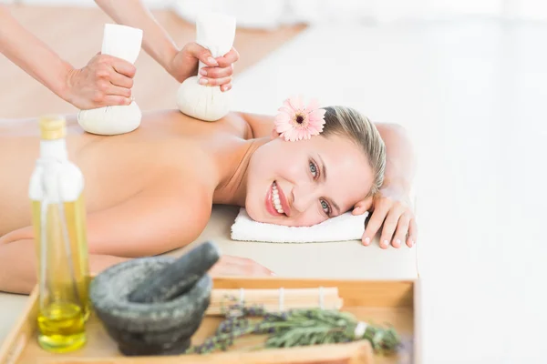 Blonde enjoying a herbal compress massage