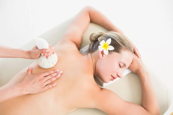 Blonde enjoying a herbal compress massage