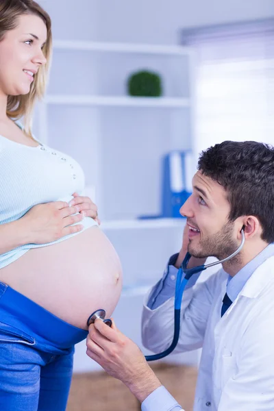 Doctor examining stomach of pregnant patient