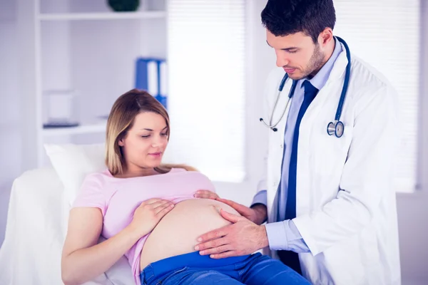 Doctor checking stomach of pregnant patient