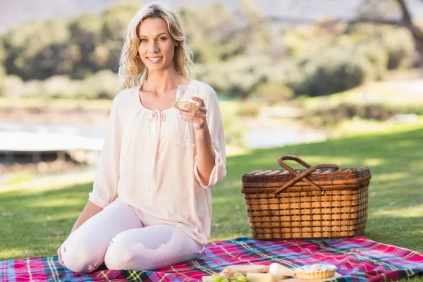 Blonde woman sitting on picnic blanket