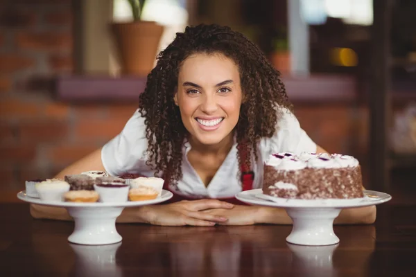 Waitress bending over chocolate cake and cupcakes