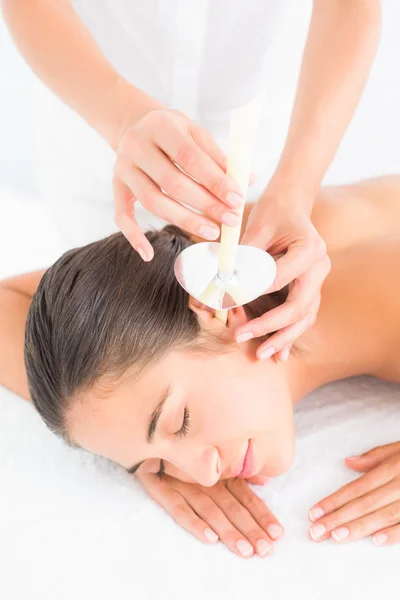 Woman receiving ear candle treatment