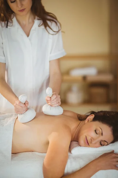 Woman getting herbal compress massage