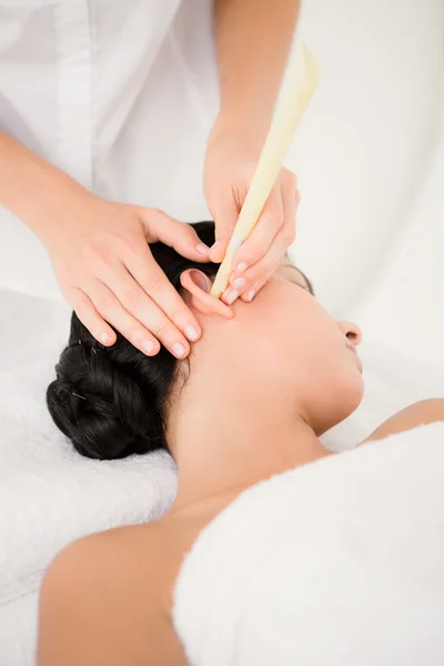 Woman receiving ear candle treatment